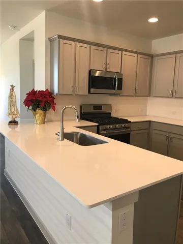 a kitchen with stainless steel appliances a sink a stove a microwave a sink and cabinets