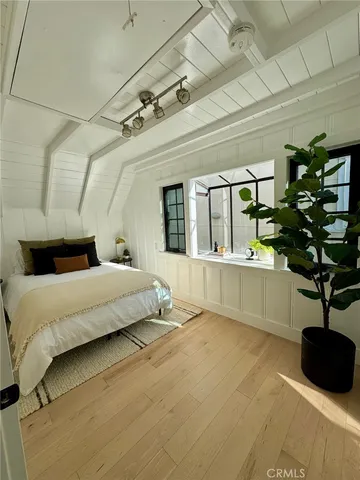 a spacious bedroom with a bed and a potted plant on the wall