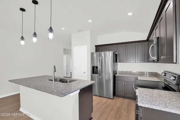 a kitchen with stainless steel appliances granite countertop a sink a refrigerator and a stove