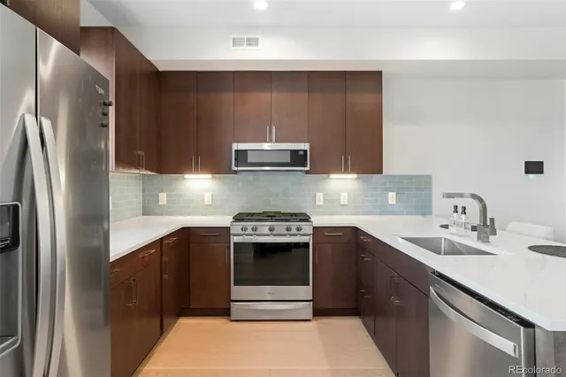 a kitchen with stainless steel appliances granite countertop a sink stove and refrigerator