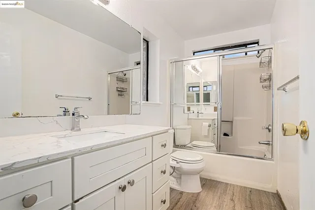 a bathroom with a granite countertop sink toilet a shower and a mirror