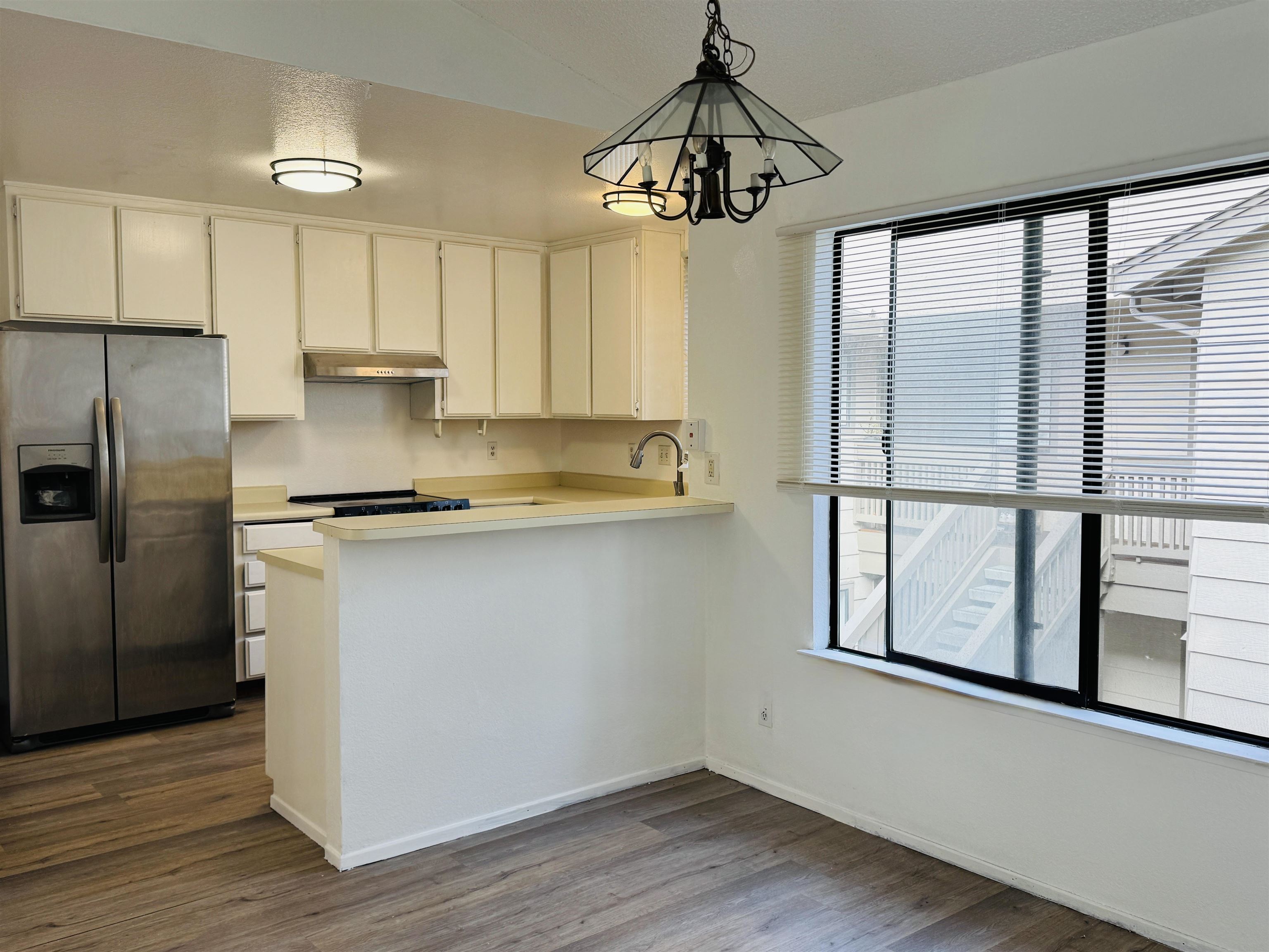 704 Windsor Hercules, CA 94547 - Photo 9 of 9 Kitchen with light countertops, stainless steel fridge, decorative light fixtures, a peninsula, and dark wood finished floors