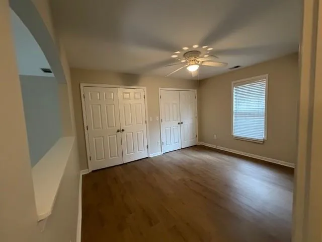 a view of an empty room with chandelier fan and wooden floor