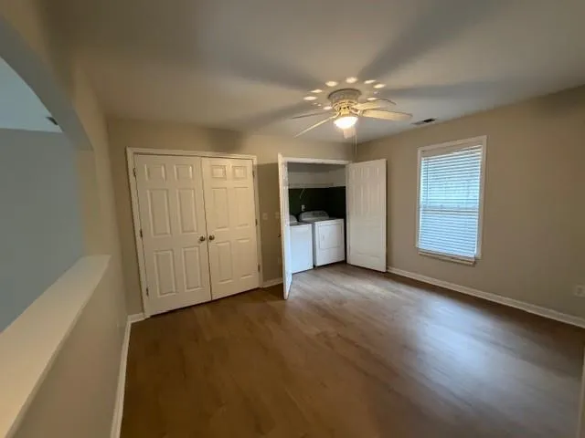 a view of an empty room with window and wooden floor