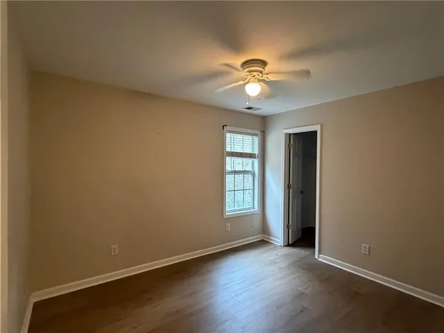 an empty room with wooden floor closet and windows