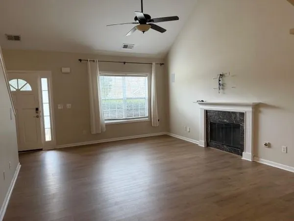 an empty room with wooden floor fireplace and windows