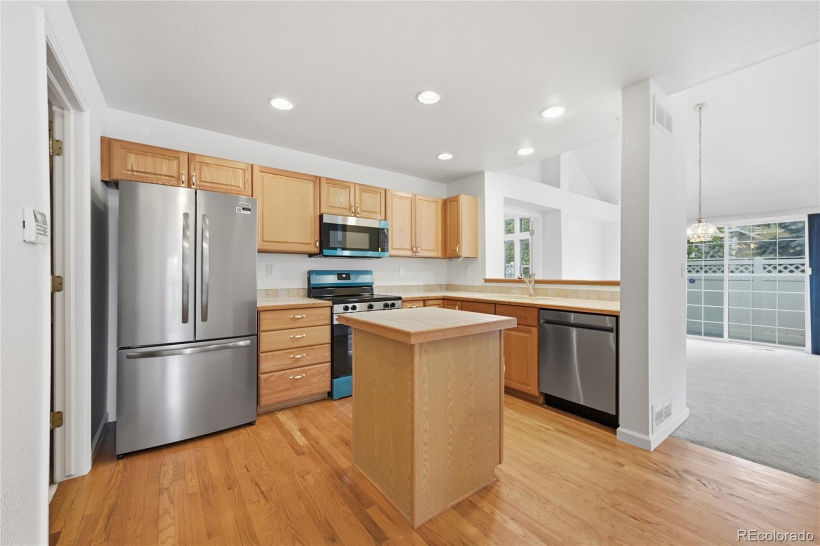 6383 Deframe Way Arvada, CO 80004 - Photo 14 of 49 a kitchen with stainless steel appliances granite countertop a refrigerator a stove a sink and a microwave
