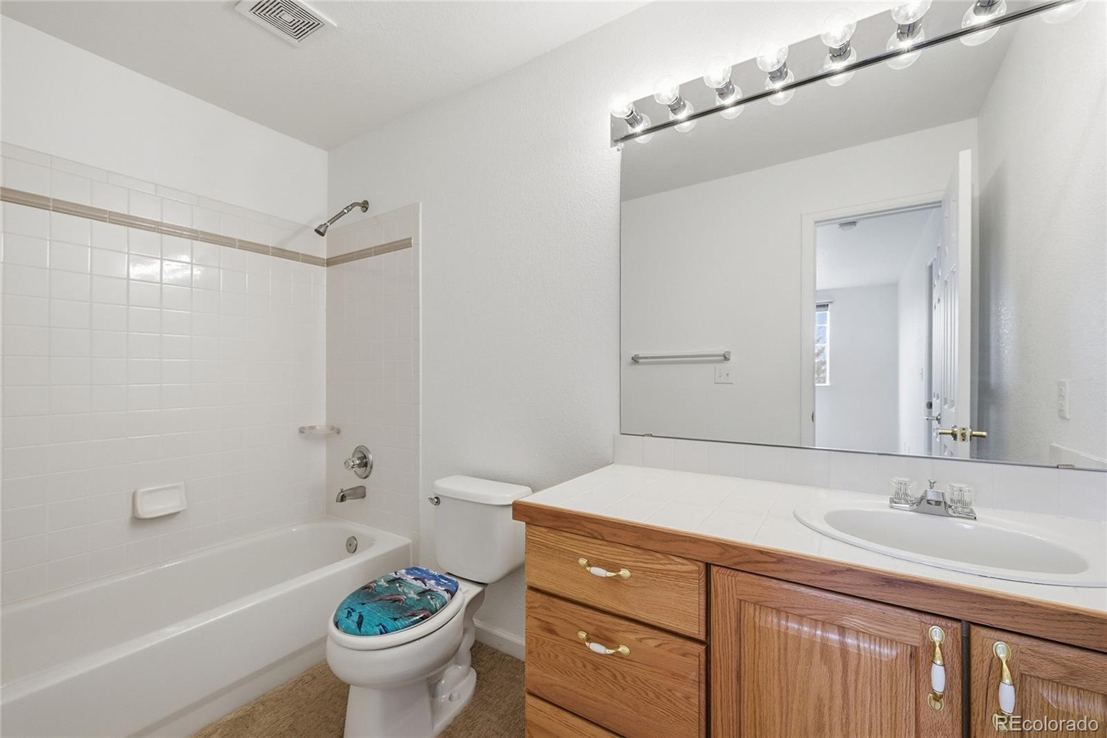 6383 Deframe Way Arvada, CO 80004 - Photo 27 of 49 a bathroom with a granite countertop sink a toilet a mirror and bathtub