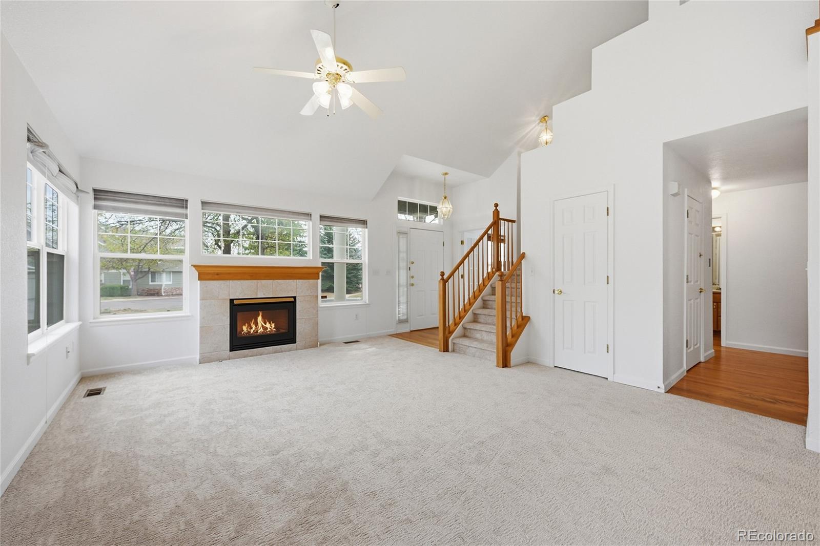 6383 Deframe Way Arvada, CO 80004 - Photo 9 of 49 an empty room with windows fireplace and a ceiling fan