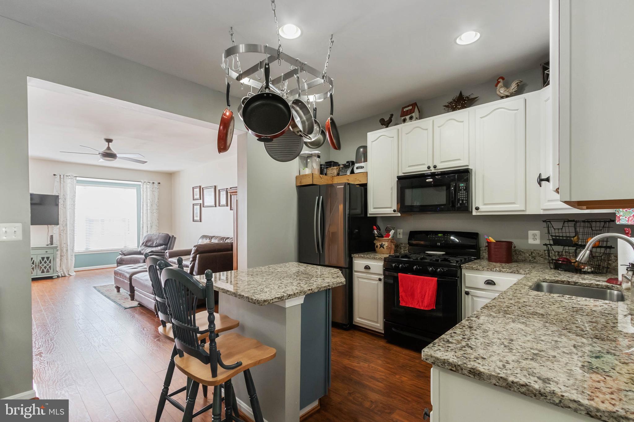 20385 Farmgate Terrace Ashburn, VA 20147 - Photo 6 of 27 a kitchen with stainless steel appliances granite countertop a stove top oven a sink dishwasher a dining table and chairs with wooden floor