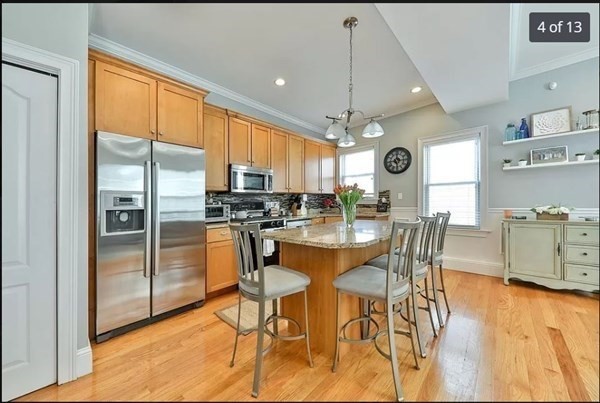 62 H Street, Unit 2 Boston, MA 02127 - Photo 4 of 12 a kitchen with stainless steel appliances kitchen island granite countertop a refrigerator a stove a dining table and chairs with wooden floor