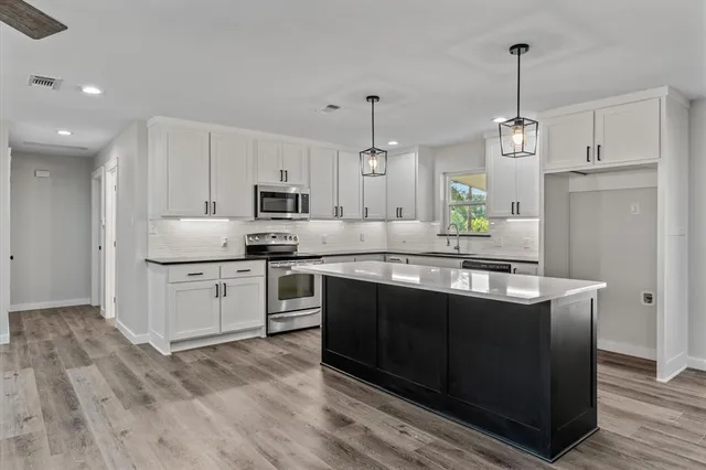 a large kitchen with cabinets wooden floor and stainless steel appliances