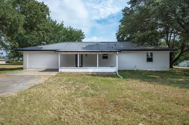 a view of pool with large trees and wooden fence