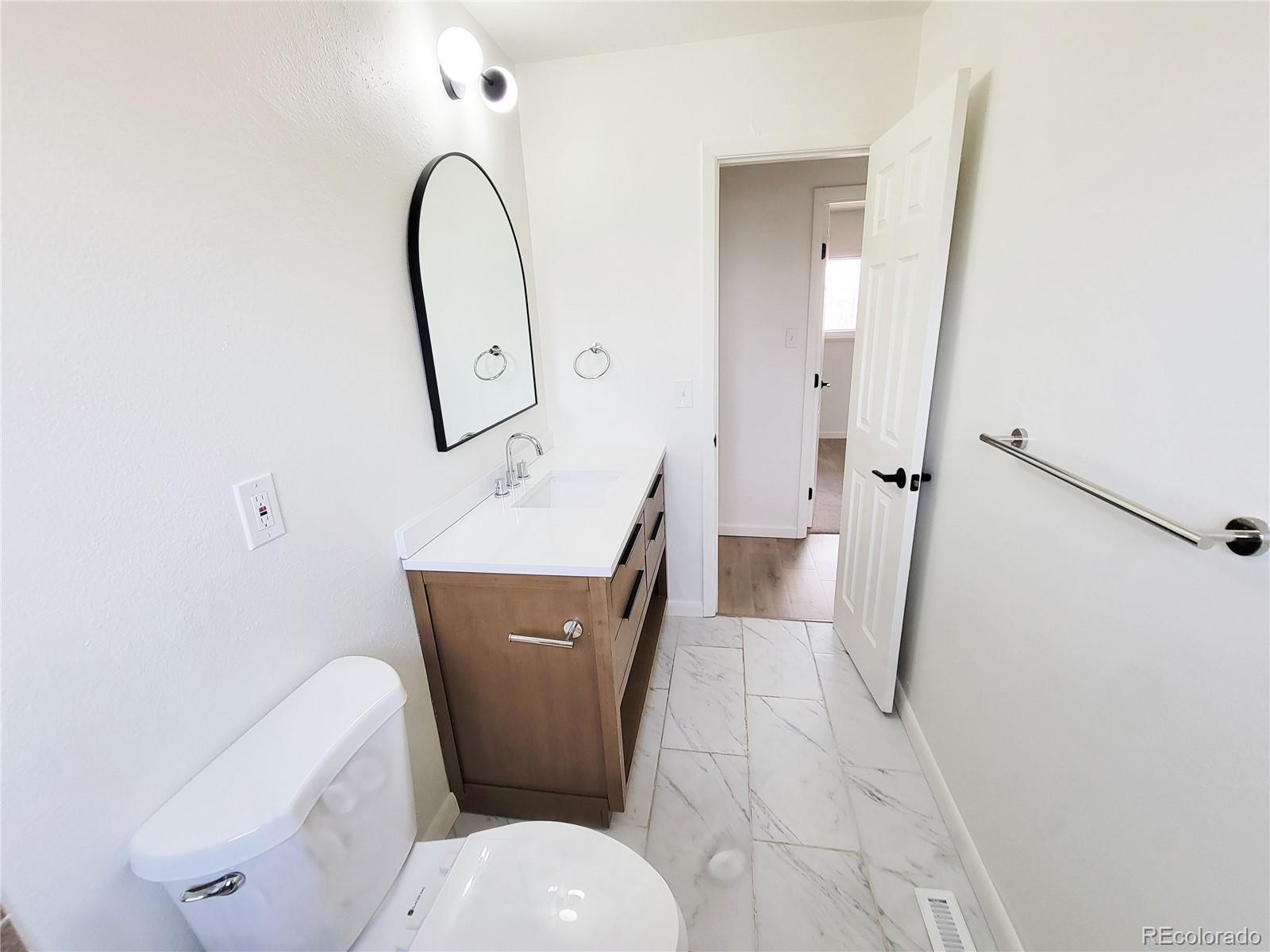 8128 Lafayette Street Denver, CO 80229 - Photo 7 of 19 a bathroom with a toilet sink and mirror