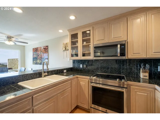 a kitchen with granite countertop a sink dishwasher stove and cabinets