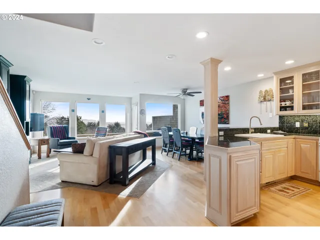 a living room with stainless steel appliances kitchen island granite countertop a refrigerator a stove a sink dishwasher and white cabinets with wooden floor