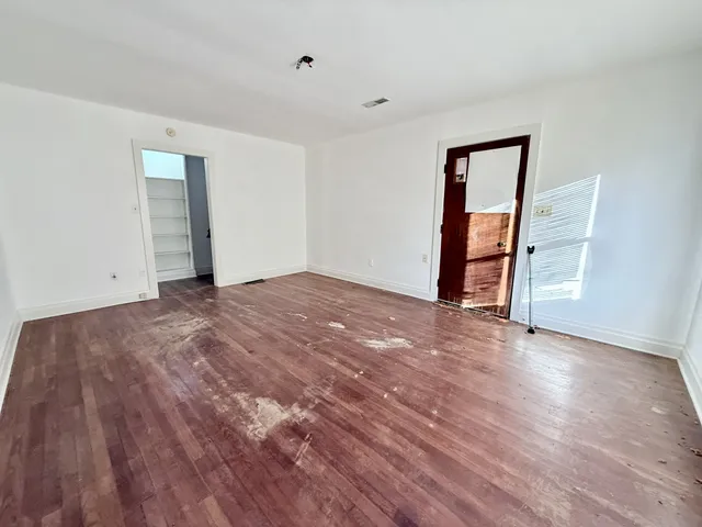 a view of an empty room with wooden floor and closet