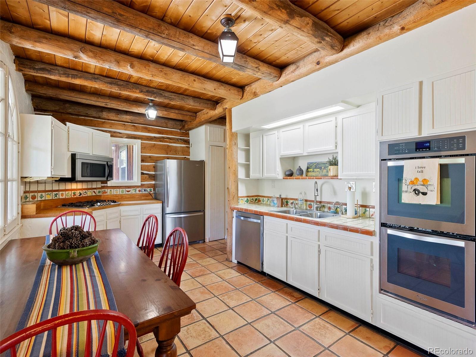 26795 Light Lane Conifer, CO 80433 - Photo 27 of 40 a kitchen with stainless steel appliances granite countertop a stove top oven a sink dishwasher and white cabinets with wooden floor