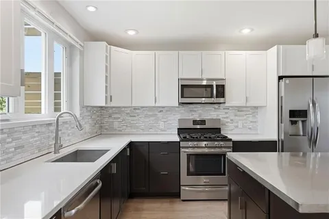 a kitchen with stainless steel appliances granite countertop a stove a sink and a microwave