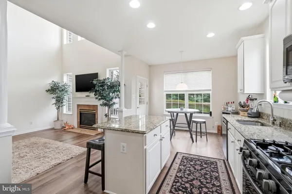 a kitchen with stainless steel appliances granite countertop a stove top oven a sink dishwasher and a fireplace with wooden floor