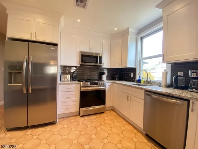 a kitchen with stainless steel appliances granite countertop a refrigerator a stove a sink and a microwave