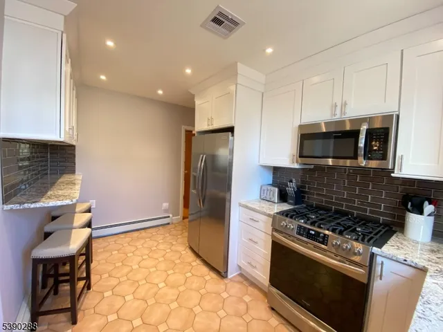 a kitchen with stainless steel appliances granite countertop a stove a refrigerator and a microwave