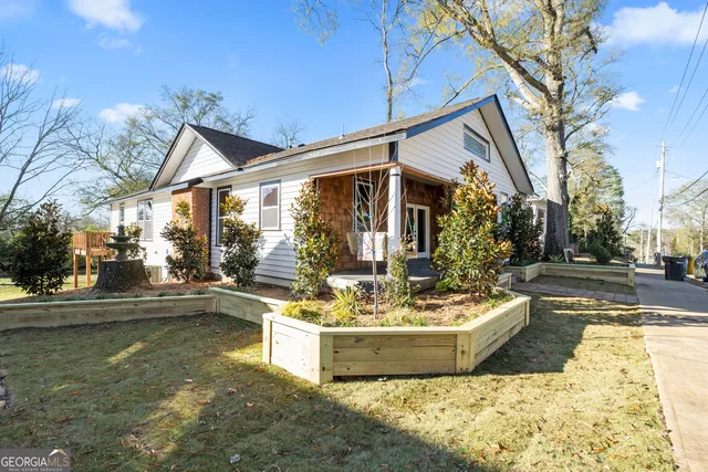 a view of a white house next to a yard with potted plants