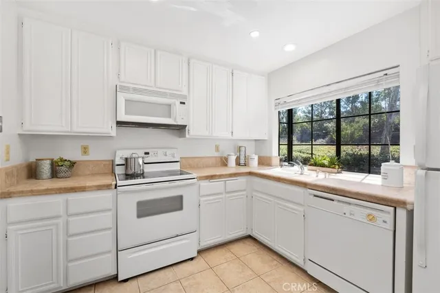 a kitchen with granite countertop white cabinets and white stainless steel appliances