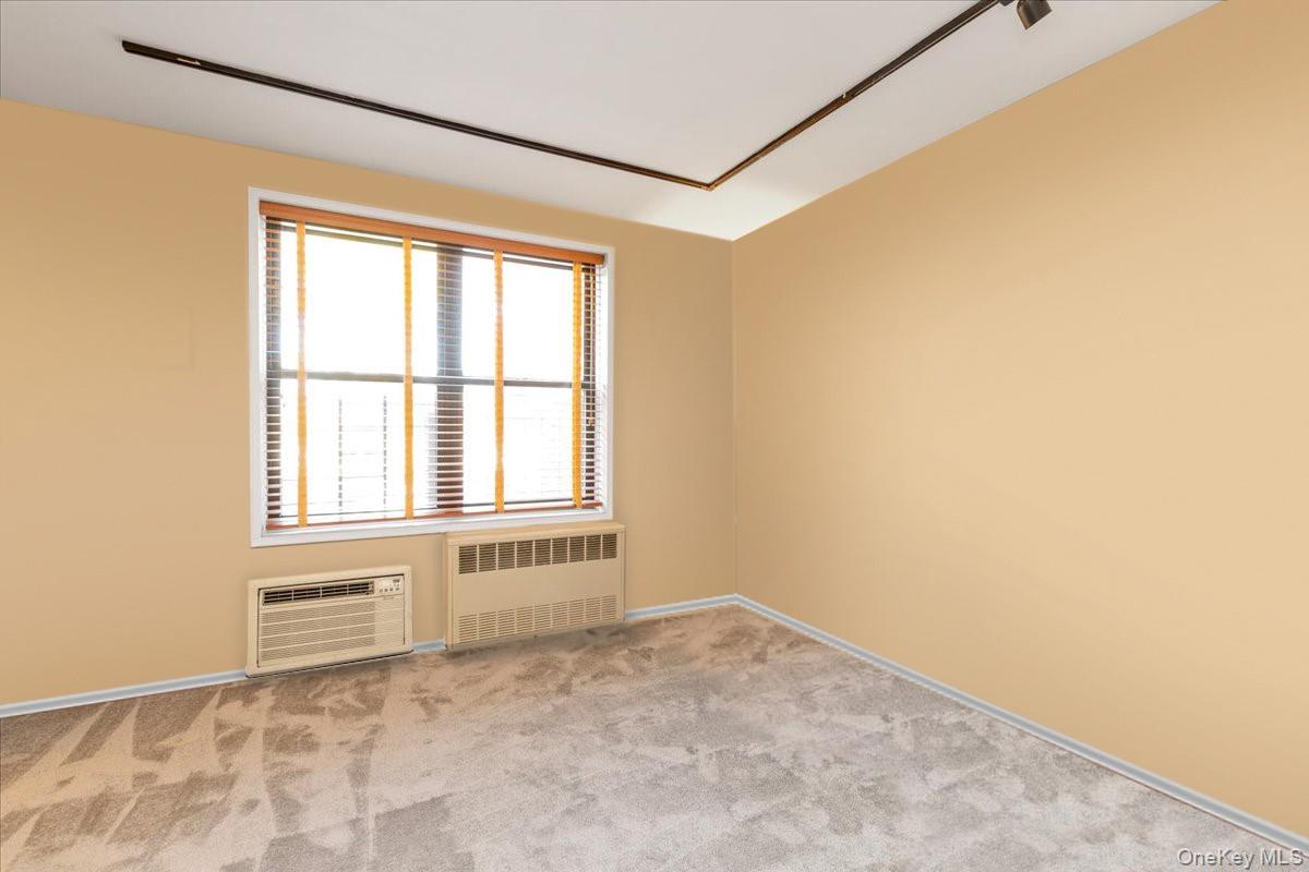 80-35 Springfield Boulevard, Unit 4F Queens, NY 11427 - Photo 16 of 24 Spare room featuring radiator, light colored carpet, and a wall mounted AC