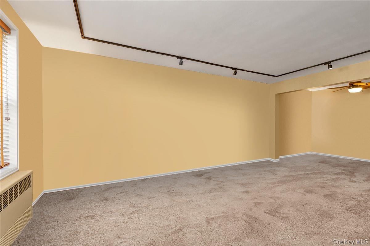 80-35 Springfield Boulevard, Unit 4F Queens, NY 11427 - Photo 16 of 24 Unfurnished room featuring track lighting, radiator, a ceiling fan, light carpet, and healthy amount of natural light