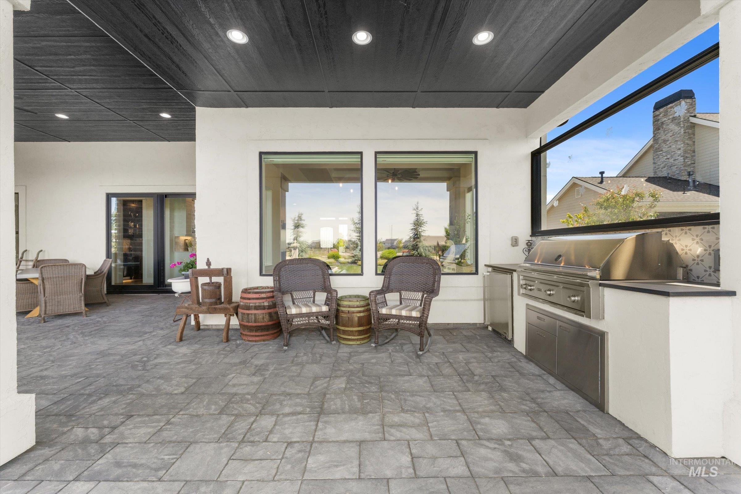 6585 South Pemberley Way Meridian, ID 83642 - Photo 41 of 43 Covered patio featuring a built-in outdoor kitchen with stainless steel appliances, stone-look countertops, and recessed lighting