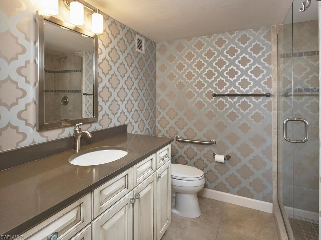3003 Gulf Shore Boulevard North, Unit 604 Naples, FL 34103 - Photo 11 of 33 a bathroom with a granite countertop sink and a mirror