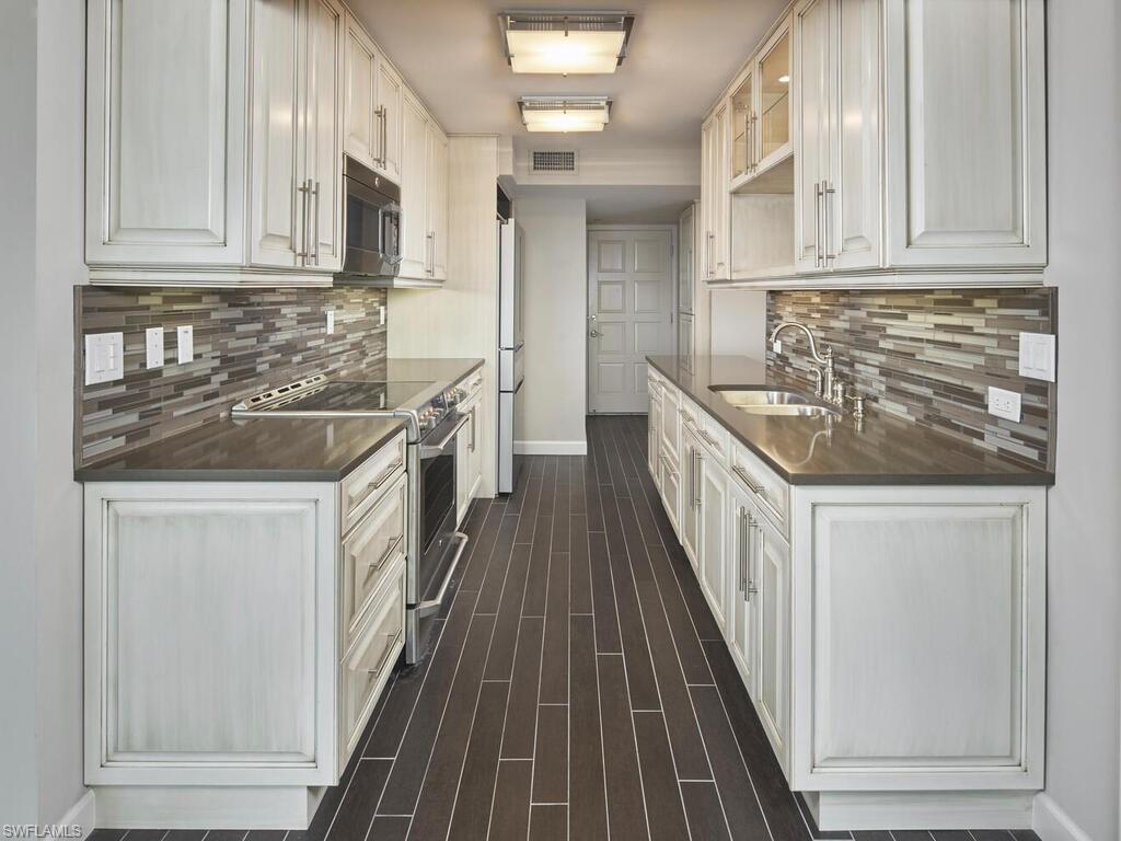 3003 Gulf Shore Boulevard North, Unit 604 Naples, FL 34103 - Photo 6 of 33 a kitchen with granite countertop a sink and dishwasher a stove top oven