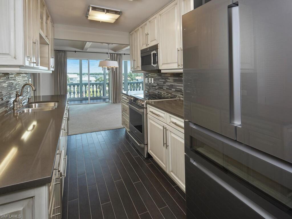 3003 Gulf Shore Boulevard North, Unit 604 Naples, FL 34103 - Photo 7 of 33 a kitchen with granite countertop a stove and a refrigerator