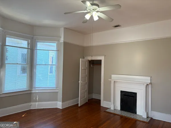 an empty room with wooden floor fireplace and windows