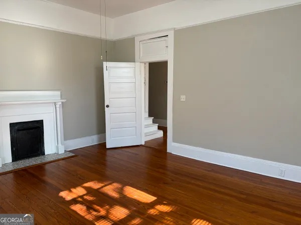 a view of an empty room with wooden floor and a fireplace