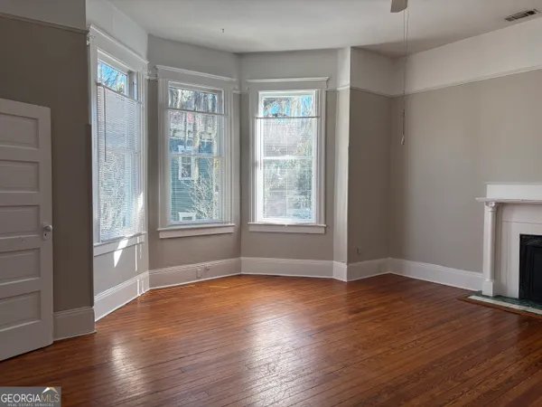 an empty room with wooden floor and windows