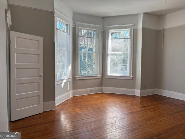 a view of an empty room with window and wooden floor