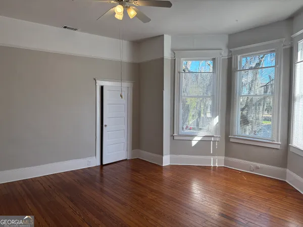 an empty room with wooden floor and windows
