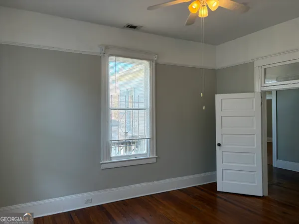 an empty room with wooden floor closet and windows