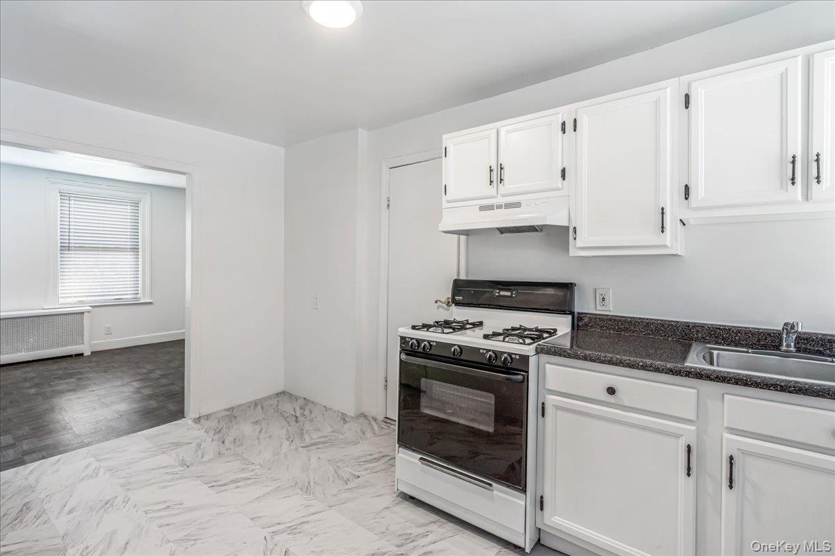 57-39 57th Road Queens, NY 11378 - Photo 19 of 31 a kitchen with granite countertop white cabinets and white stove