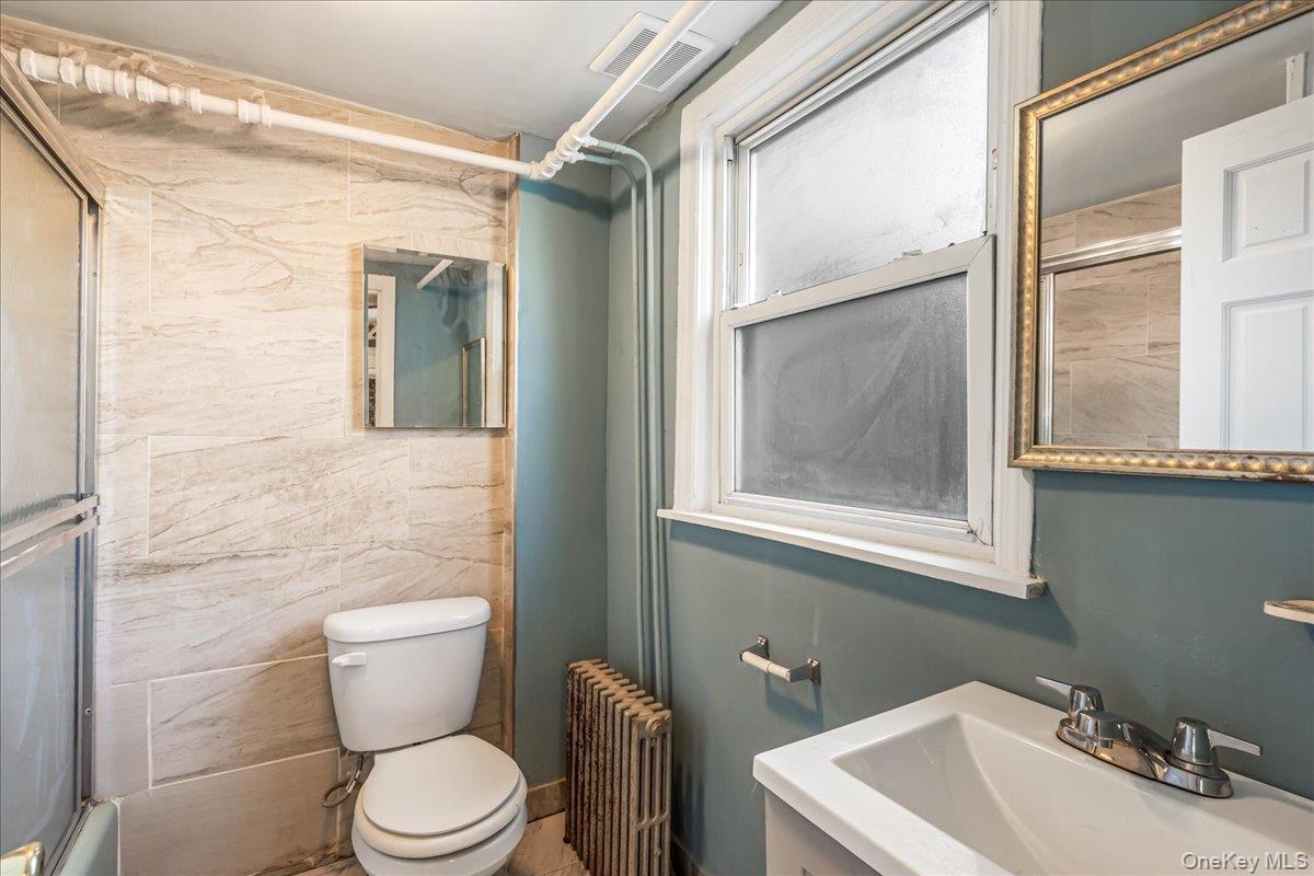 57-39 57th Road Queens, NY 11378 - Photo 8 of 31 a bathroom with a toilet a sink and a window