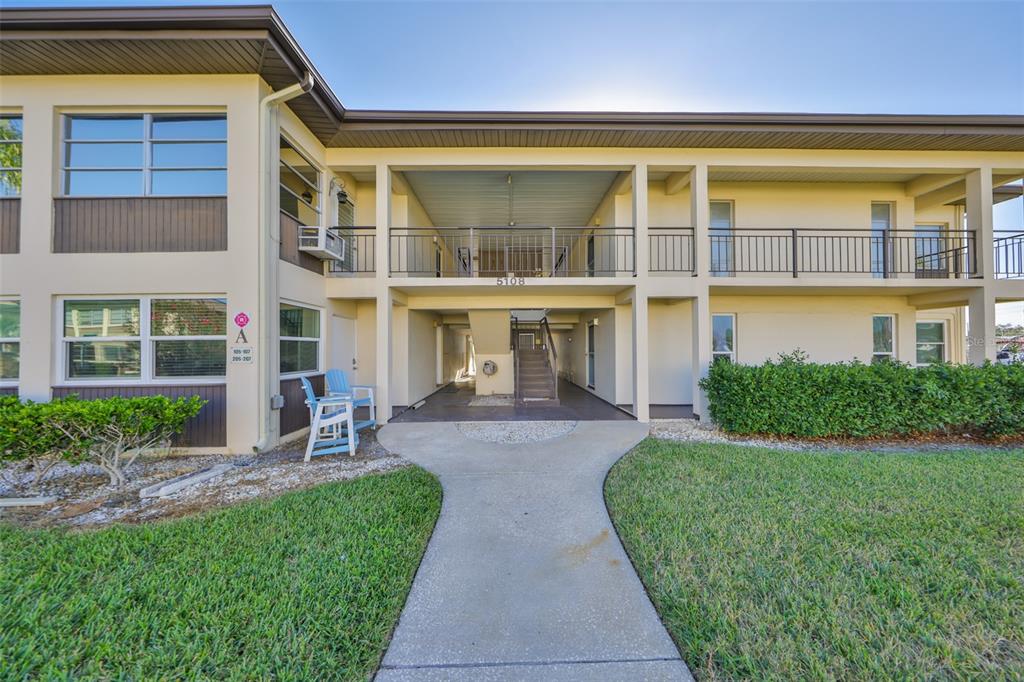 5108 Amulet Drive, Unit 206 New Port Richey, FL 34652 - Photo 1 of 1 a front view of a building with a garden and plants