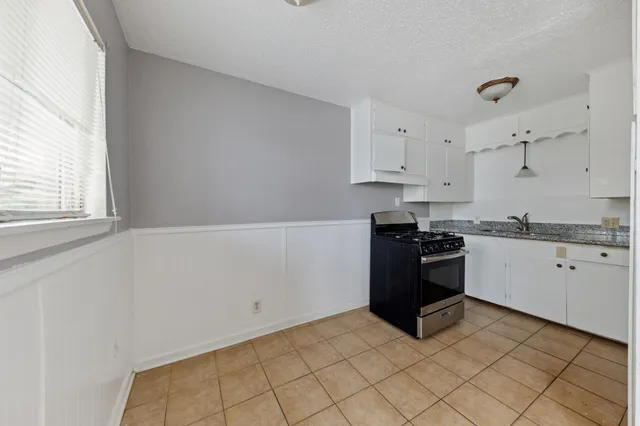 a kitchen with granite countertop white cabinets and black appliances