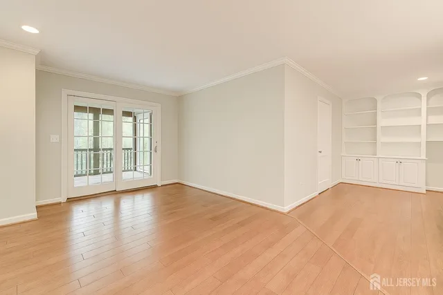 a view of an empty room with wooden floor and windows