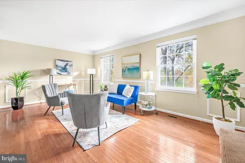 a living room with furniture a potted plant and a wooden floor