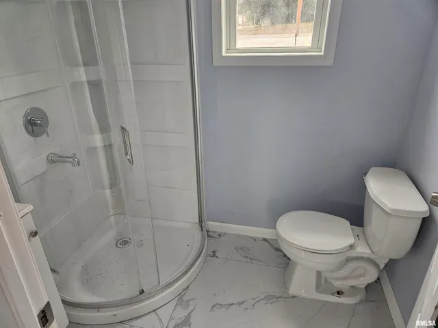 a white toilet sitting next to a shower