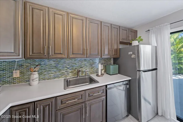 a kitchen with stainless steel appliances granite countertop a refrigerator a sink a stove and white cabinets