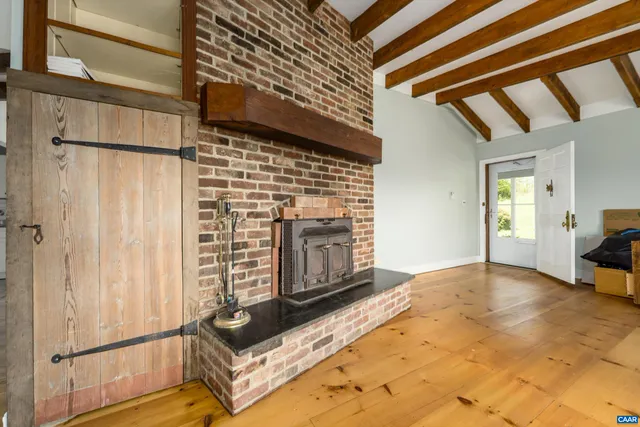 a view of an empty room with wooden floor and a fireplace