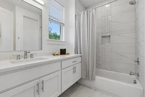 a bathroom with a double vanity sink a mirror and a bathtub
